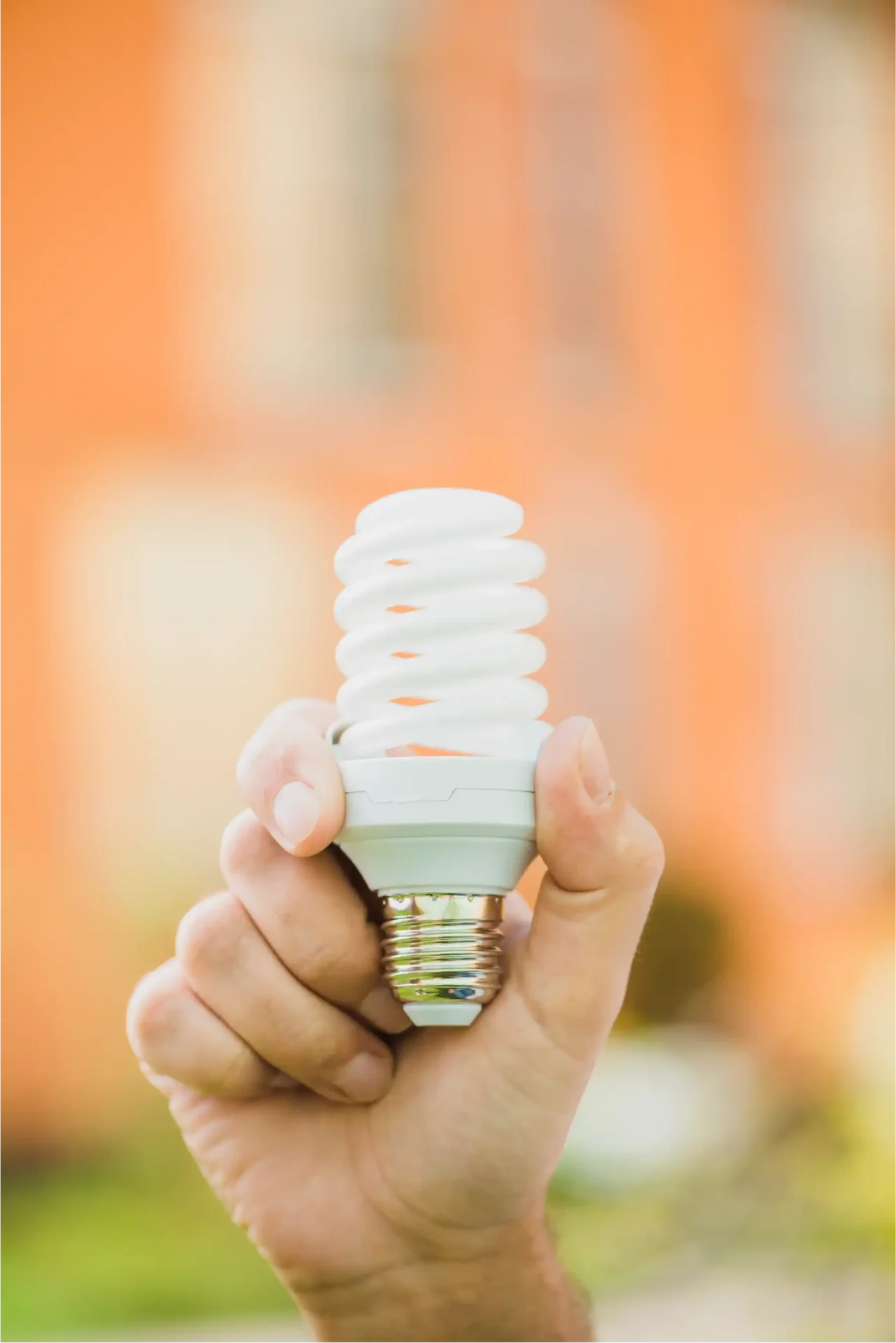 hand holding energy saving compact fluorescent light bulb outdoors scaled 1